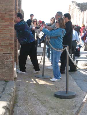 Visitor crosses a rope barrier to take a picture of a mosaic. Behaviour like this could be lessened through active enforcement (Pompeii).